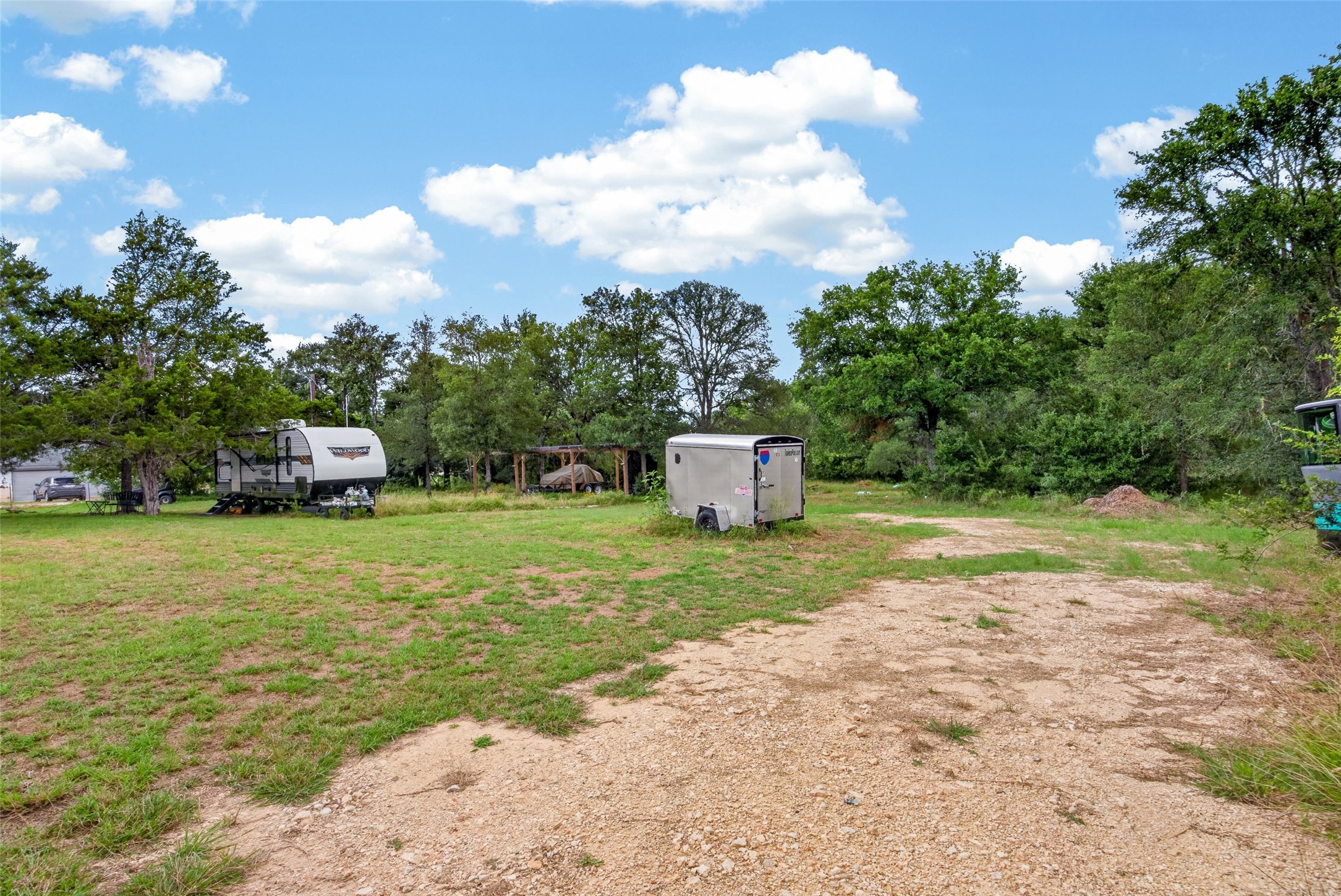 266 Beaver Road Elgin, TX 78621 - Photo 11 of 40 A spacious lot offering ample room for potential development, bordered by mature trees under a clear sky.