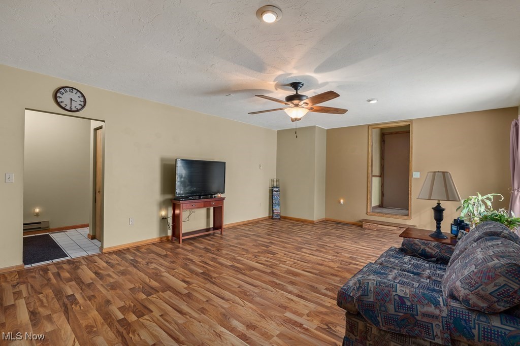 8238 Ruff Road West Salem, OH 44287 - Photo 12 of 27 Unfurnished living room featuring baseboards, a ceiling fan, a baseboard radiator, a textured ceiling, and light wood-style floors