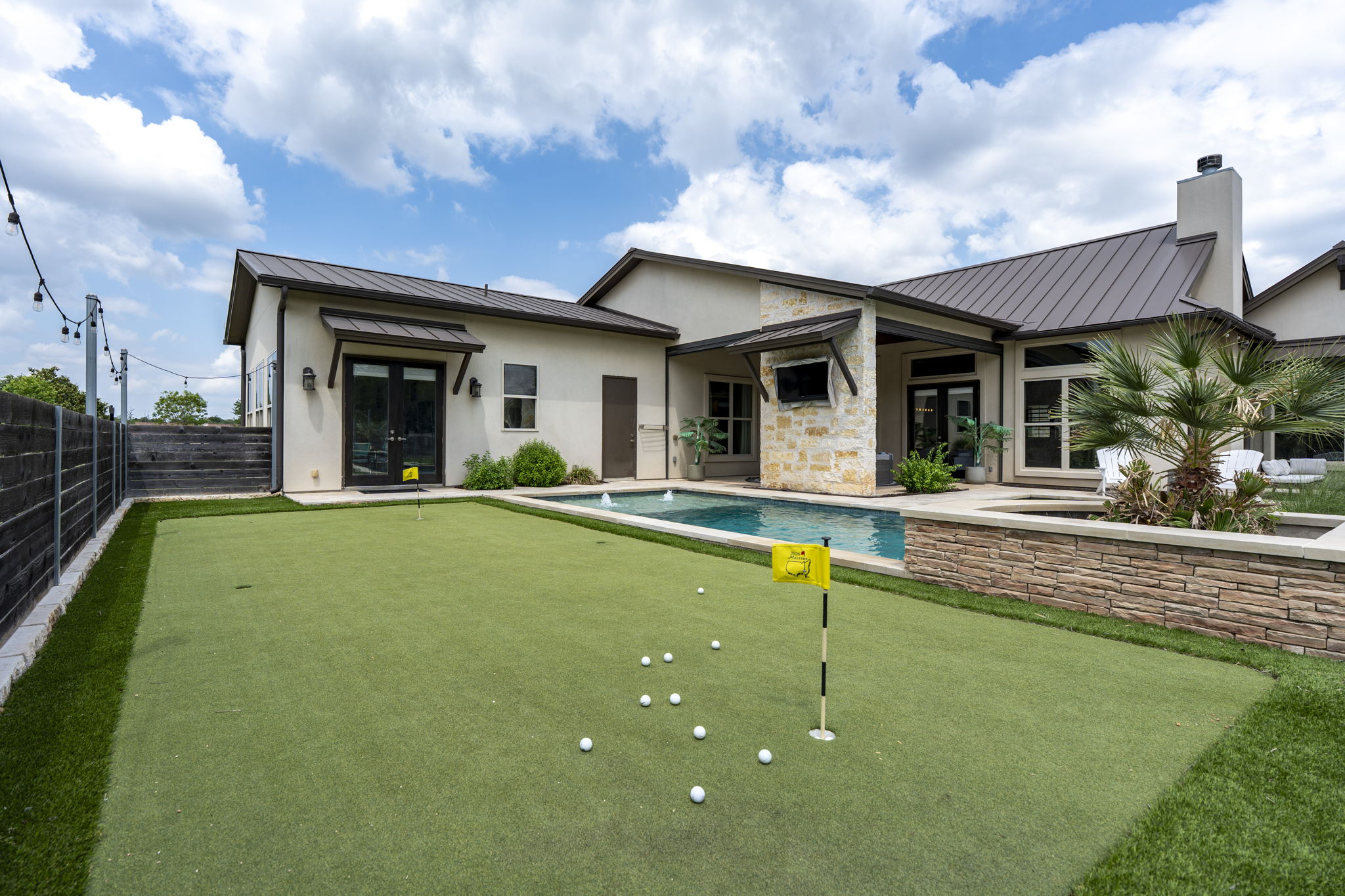 16202 Remuda Trail Buda, TX 78610 - Photo 30 of 40 The property features a private putting green, a swimming pool with a fountain, and a stone-clad raised planter