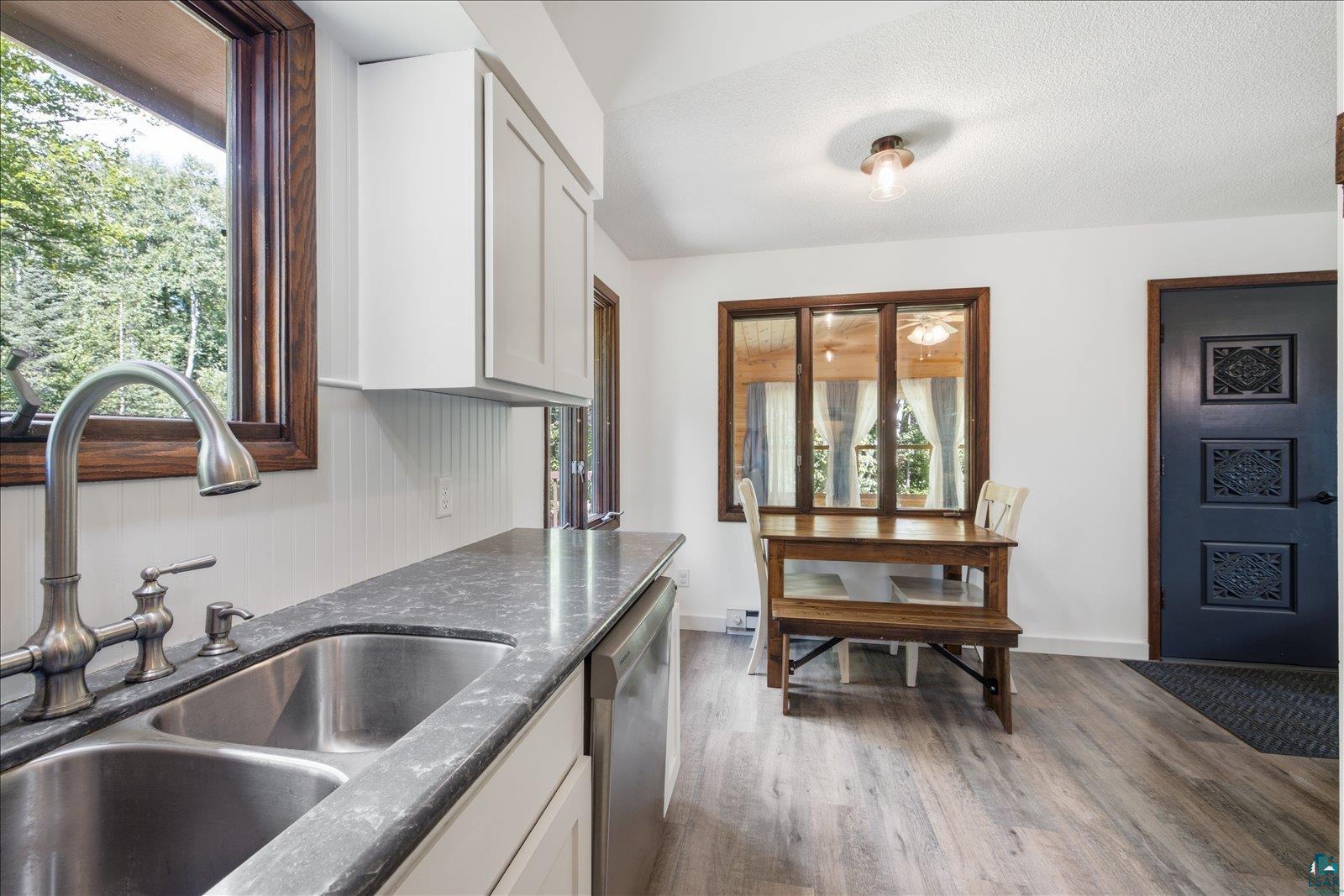 6377 Bergstrom Road Saginaw, MN 55779 - Photo 7 of 20 Kitchen space featuring a dual basin stainless steel sink with a high-arch brushed nickel faucet, light gray countertops, white cabinetry, and wood-finish flooring