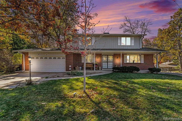 a view of a house with a small yard and large trees