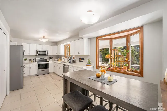 a open kitchen with granite countertop a stove a sink dishwasher a dining table and chairs with wooden floor