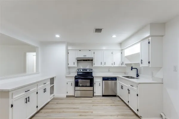 a kitchen with white cabinets stainless steel appliances and sink