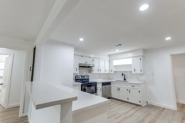 a kitchen with white cabinets and sink