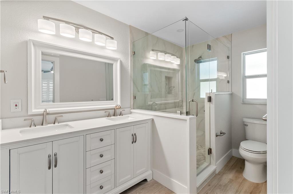 54 Liberty Lane Naples, FL 34112 - Photo 19 of 30 Bathroom#1 featuring double vanity, a marble finish shower, and light wood-style floors