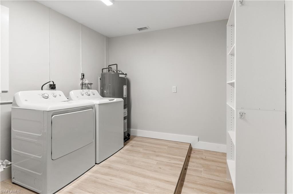 54 Liberty Lane Naples, FL 34112 - Photo 21 of 30 Laundry room AND STORAGE with light wood-style flooring, washer and dryer, and water heater