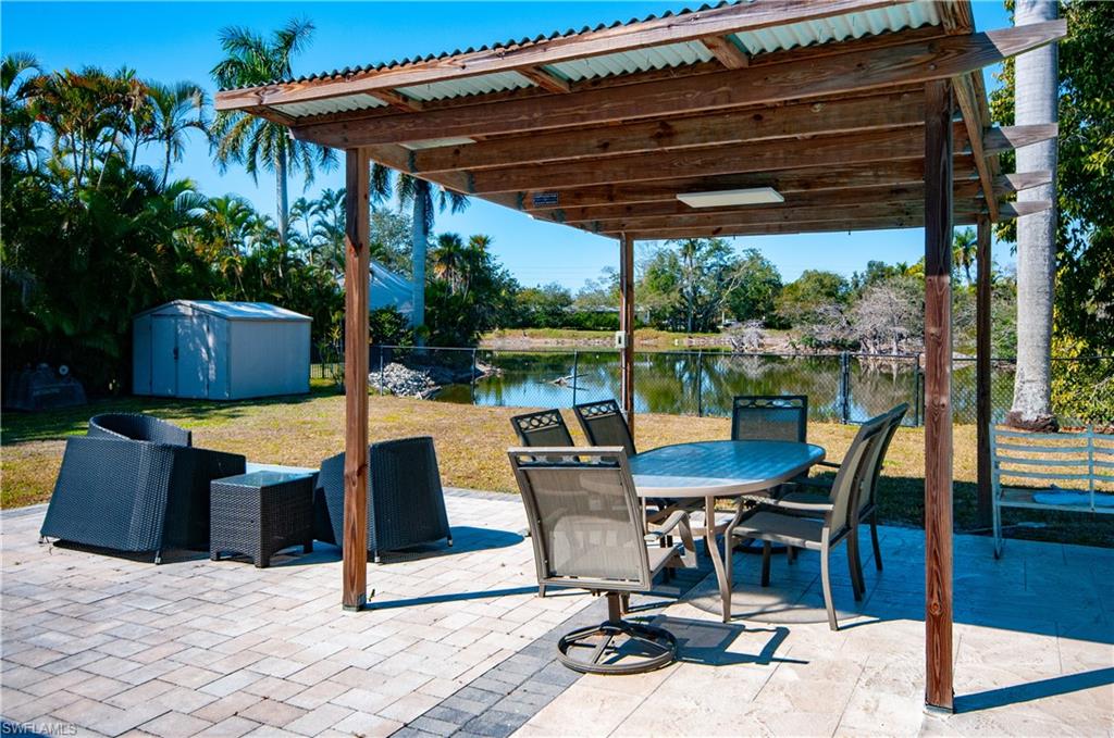 54 Liberty Lane Naples, FL 34112 - Photo 27 of 30 View of patio featuring a storage unit, a water view, and outdoor dining space