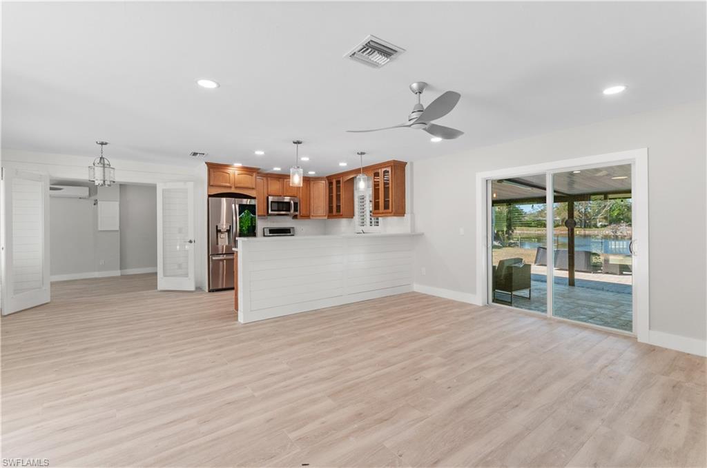 54 Liberty Lane Naples, FL 34112 - Photo 6 of 30 Unfurnished living room with light wood-type flooring, ceiling fan, and hanging lights