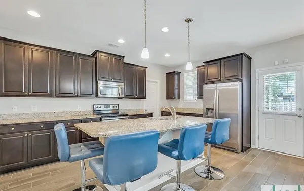 a kitchen with sink a refrigerator and chairs