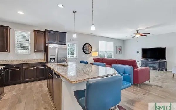 a large kitchen with stainless steel appliances granite countertop a stove a sink dishwasher a dining table and chairs with wooden floor