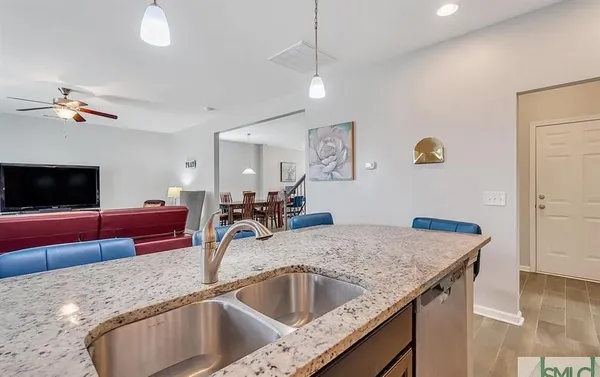 a kitchen with granite countertop a sink a counter top space and living room view
