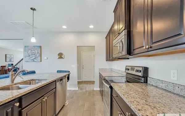 a kitchen with granite countertop stainless steel appliances sink stove microwave and cabinets