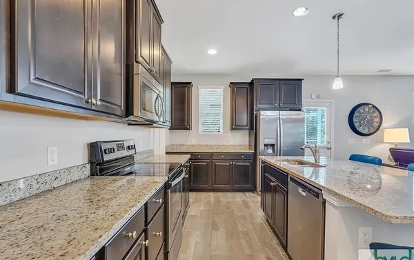 a kitchen with stainless steel appliances granite countertop a sink a stove and a wooden floors