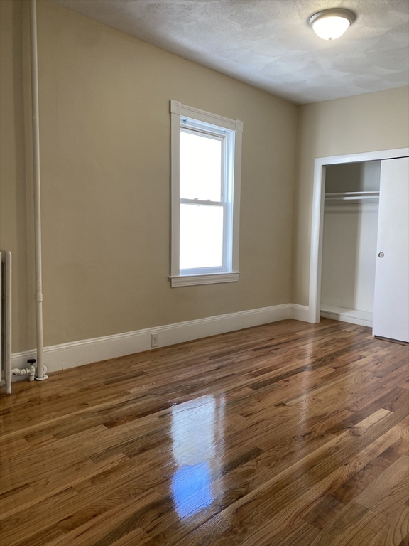 34 Porter Street, Unit 2 Malden, MA 02148 - Photo 7 of 12 an empty room with wooden floor and windows