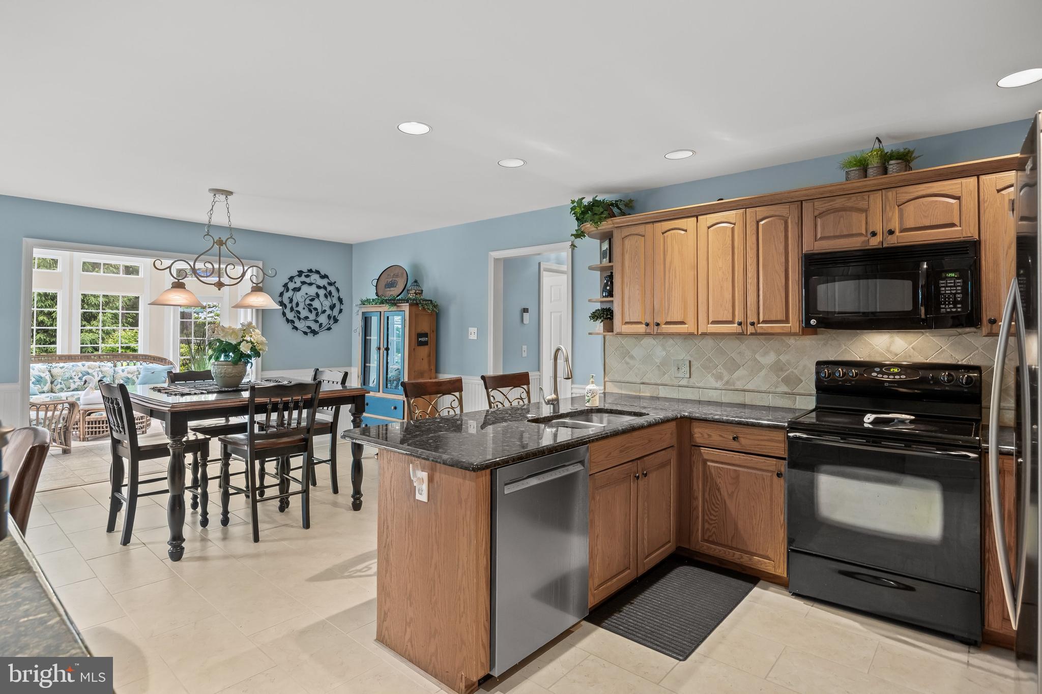 4 False Heather Way Medford, NJ 08055 - Photo 10 of 48 a kitchen with stainless steel appliances granite countertop a stove top oven a sink dishwasher a dining table and chairs with wooden floor