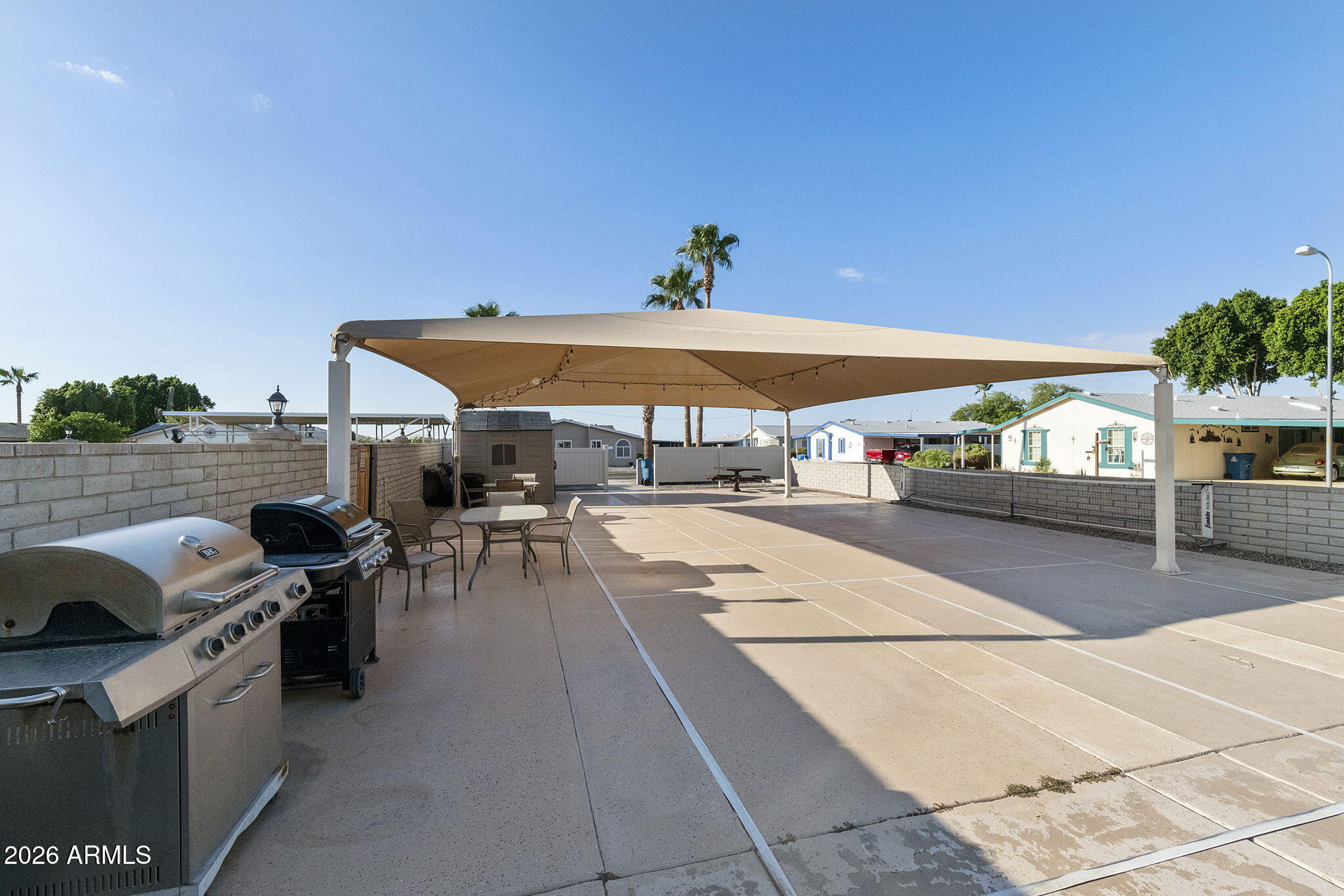 3700 South Tomahawk Road, Unit 73 Apache Junction, AZ 85119 - Photo 48 of 49 a view of a patio with dining table and chairs under an umbrella
