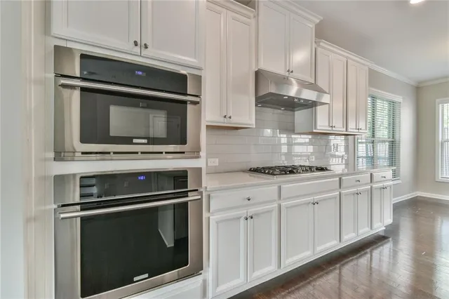 a kitchen with stainless steel appliances white cabinets and a stove a oven with wooden floor