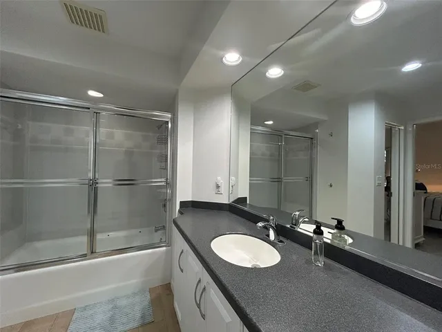 a bathroom with a double vanity sink and mirror with bathtub