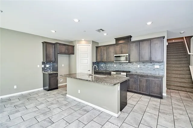 a kitchen with stainless steel appliances granite countertop a sink stove and refrigerator