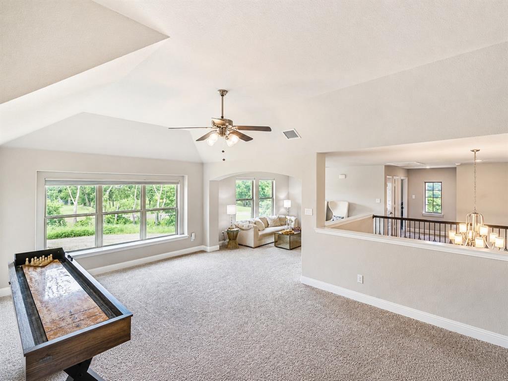 25 Morrison Road Howe, TX 75459 - Photo 14 of 27 Spacious second-level living area featuring vaulted ceilings, a ceiling fan with integrated lighting, multiple windows, and plush carpeting
