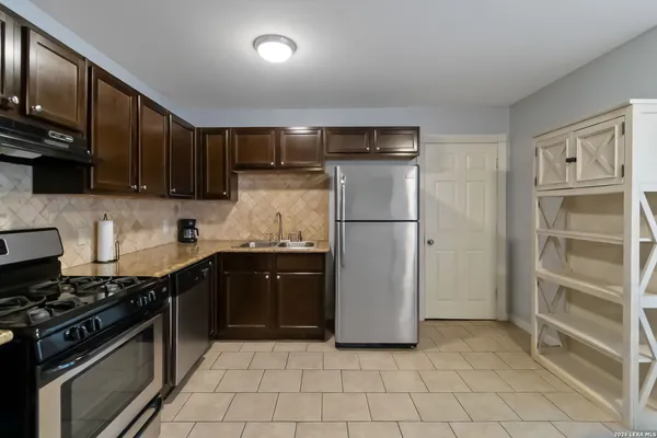 a kitchen with granite countertop a refrigerator and a stove top oven