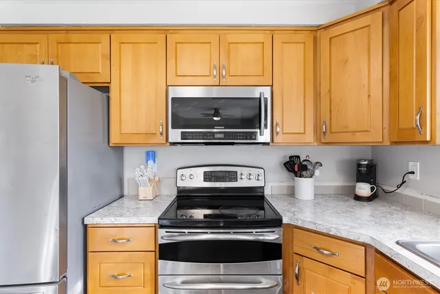 a kitchen with stainless steel appliances granite countertop a stove a sink and a microwave