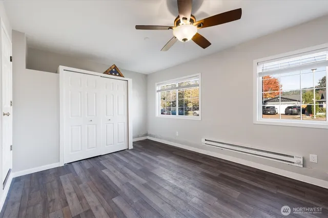 an empty room with wooden floor chandelier fan and windows
