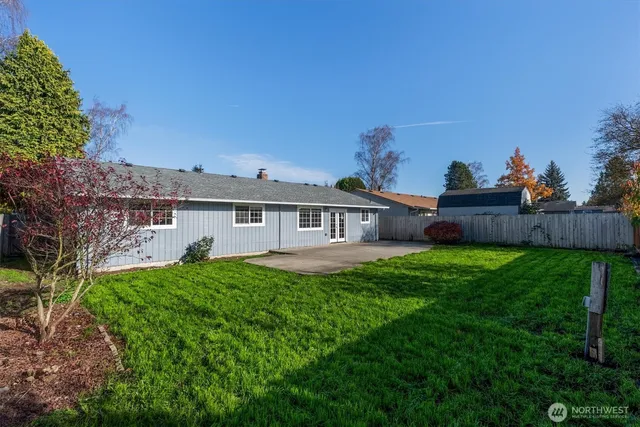 a view of a house with a big yard potted plants and large tree