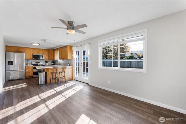 a open kitchen with granite countertop a stove top oven a sink a dining table and chairs with wooden floor