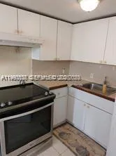 a kitchen with granite countertop white cabinets and black appliances
