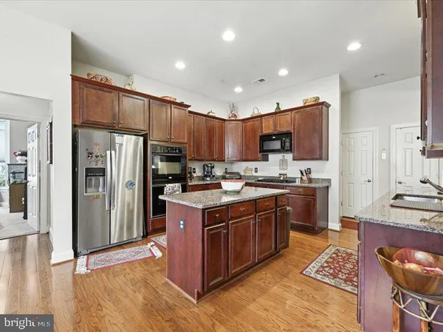 a kitchen with stainless steel appliances granite countertop a stove top oven a refrigerator a sink and a center island