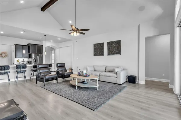 a living room with furniture a flat screen tv and a ceiling fan