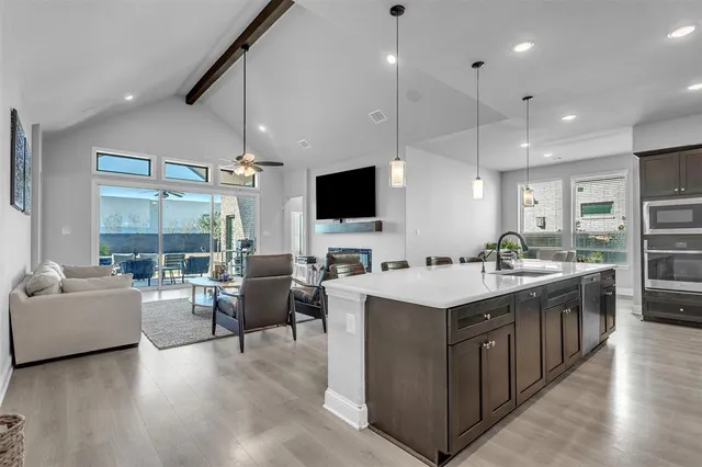 a living room with stainless steel appliances kitchen island furniture and a flat screen tv
