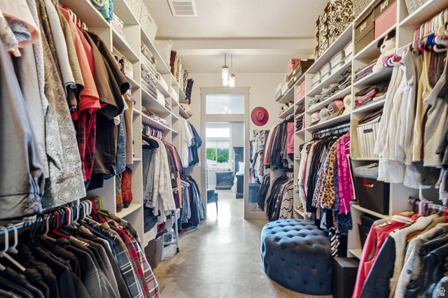 560 Aspen Road Francis, UT 84036 - Photo 28 of 59 Spacious walk-in closet featuring extensive built-in shelving and clothing rods throughout, polished concrete flooring, recessed lighting, and a blue upholstered ottoman