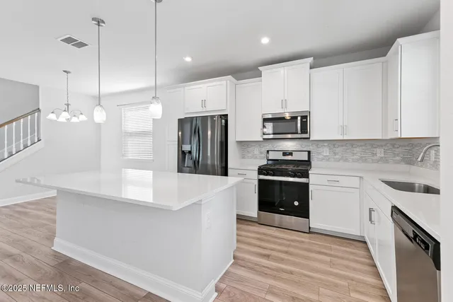 a large kitchen with stainless steel appliances kitchen island granite countertop a stove a sink and a refrigerator