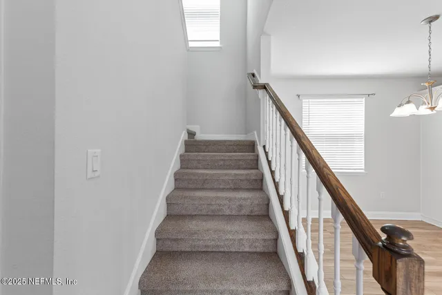 a view of staircase with wooden floor and white walls
