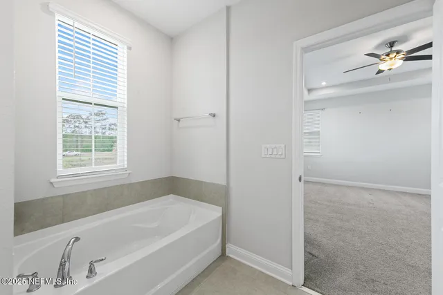 a white bath tub sitting in a bathroom next to a window