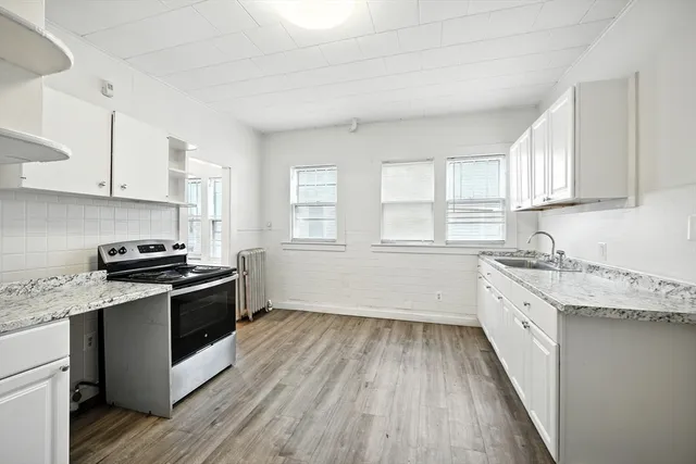 a kitchen with granite countertop wooden floors and white stainless steel appliances