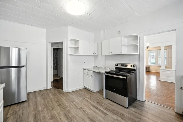 a kitchen with granite countertop a refrigerator and a stove top oven