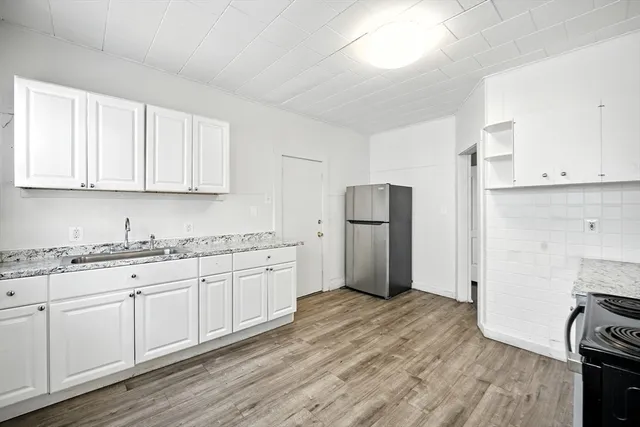 a kitchen with stainless steel appliances granite countertop a refrigerator sink and white cabinets