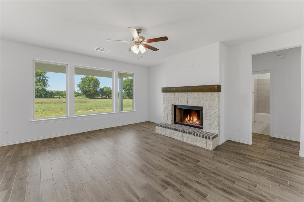 130 Fossil Canyon Drive Rhome, TX 76078 - Photo 8 of 25 Spacious interior featuring wood-finish flooring, a stone-clad fireplace with a brick hearth and wood mantel, and a ceiling fan