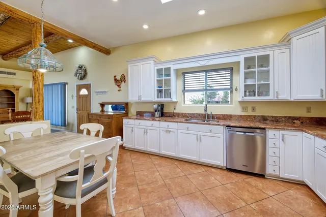 a kitchen with granite countertop lots of white cabinets a sink and dishwasher