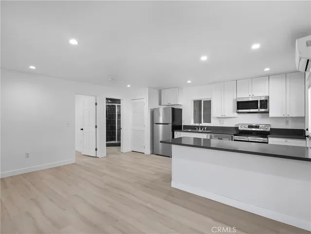 a large kitchen with stainless steel appliances granite countertop a large counter top and a stove with wooden floor