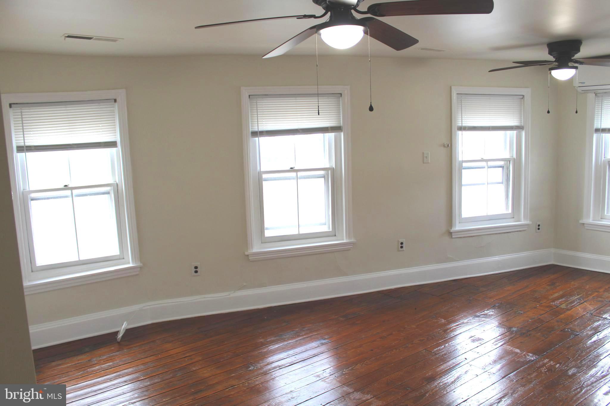 4417 Baker Street Philadelphia, PA 19127 - Photo 31 of 50 an empty room with wooden floor chandelier fan and windows