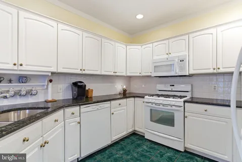 a kitchen with granite countertop white cabinets and white appliances