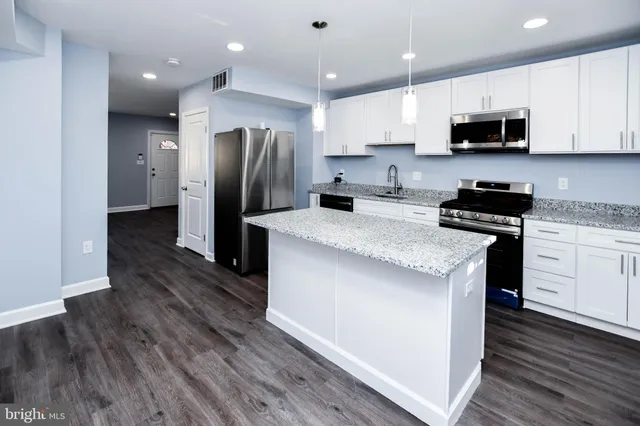 a kitchen with granite countertop a refrigerator stove top oven and sink
