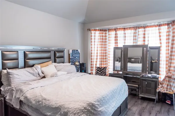 a bedroom with a large bed and wooden floor