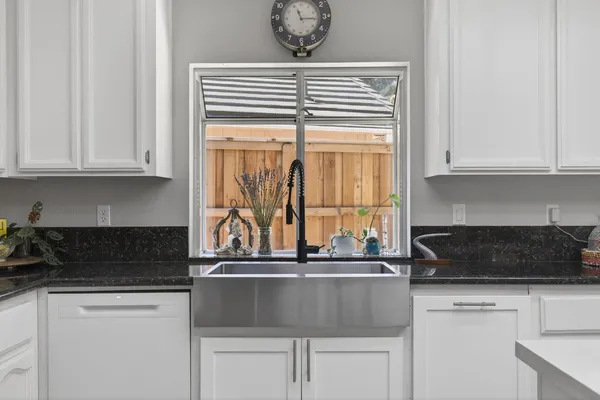 a kitchen with granite countertop a stove and white cabinets