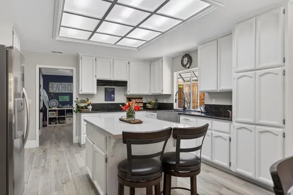 a view of kitchen center island wooden floor cabinets and refrigerator