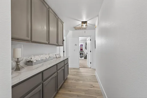 a hallway with kitchen island wooden floor stainless steel appliances and cabinets